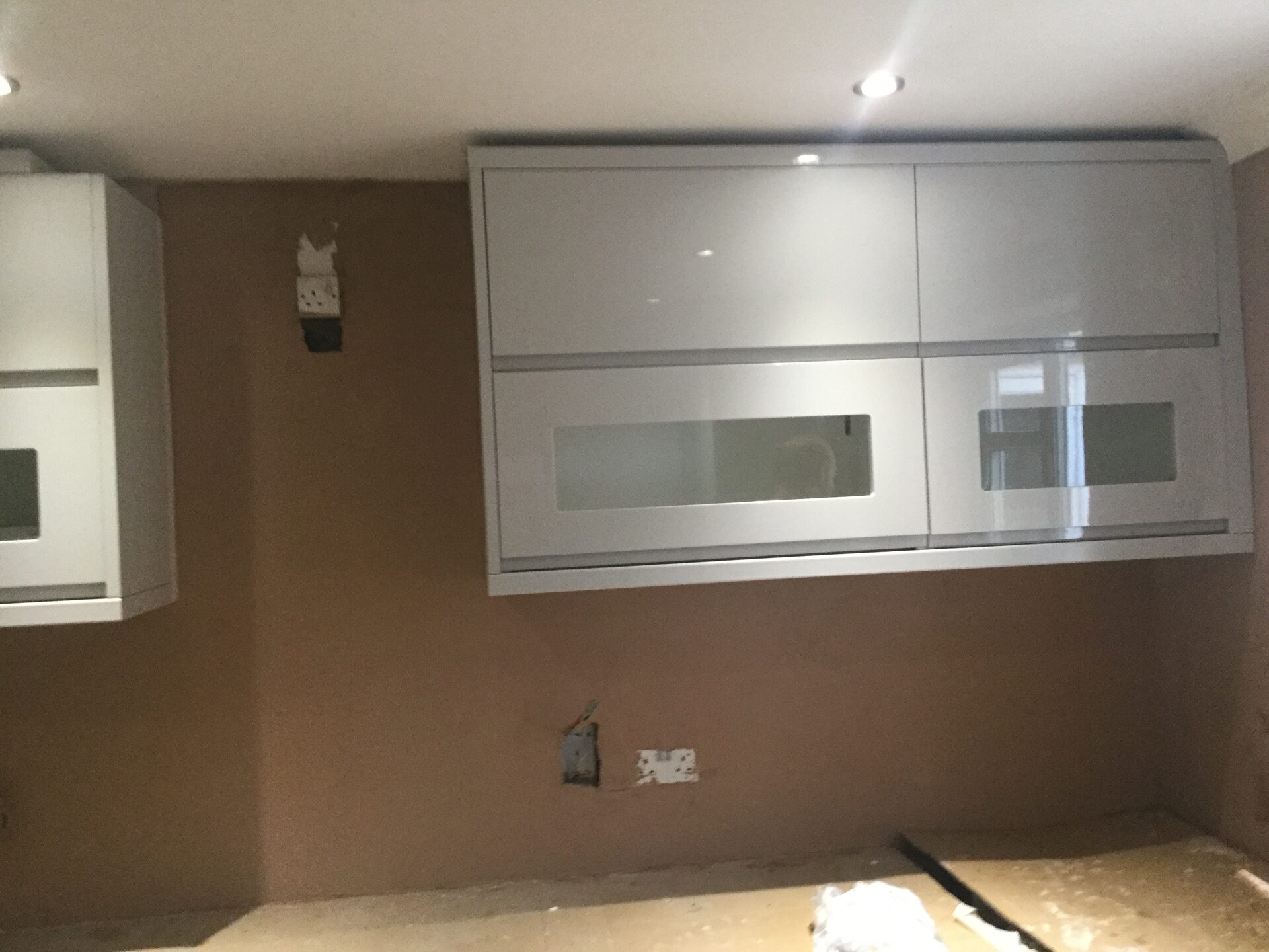 Handmade grey kitchen wall units being fitted